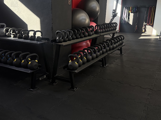 Strefa kettlebell w Power Place Grudziądz: stojaki z kettlebellami, piłki i gumy oporowe na czarnych matach